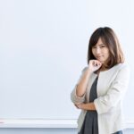 Woman with arms crossed in front of whiteboard