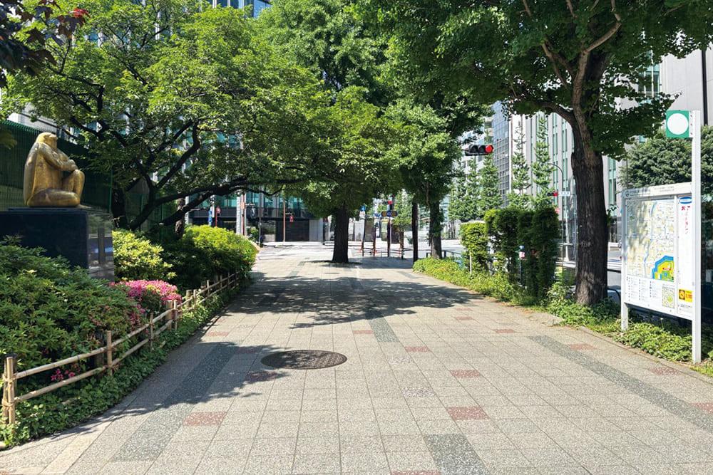 Lush Hibiya Street with sculptures and greenery.