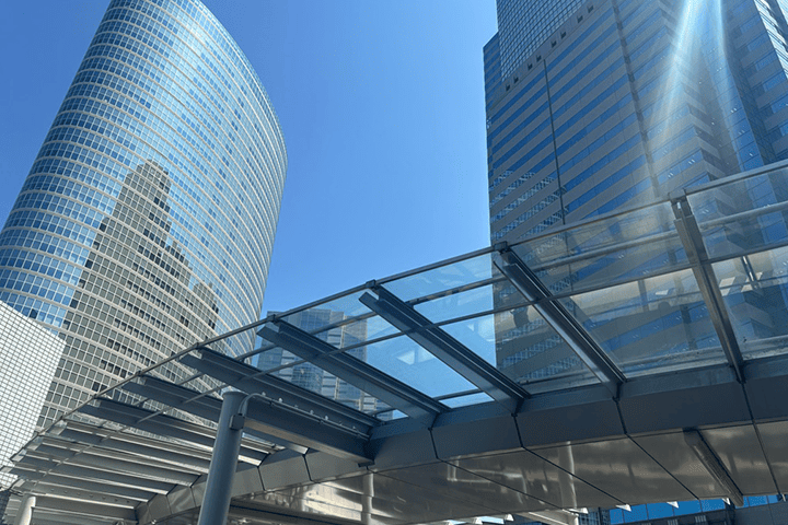 A low-angle view of the towering skyscrapers in front of Shinagawa Station, featuring a walkway with a glass ceiling.