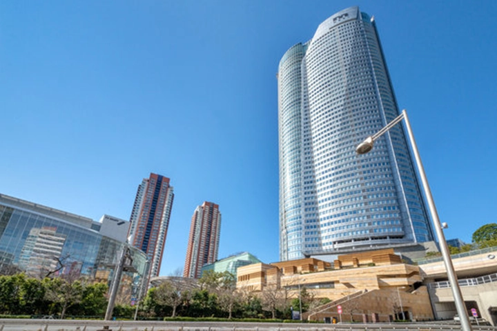 The towering Roppongi Hills Mori Tower and other modern buildings against a clear blue sky.