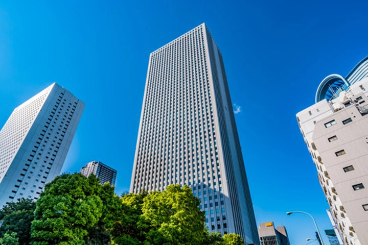 A low-angle view of the towering high-rise buildings of Sunshine City against a clear blue sky.
