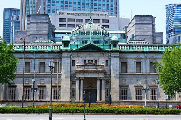 Exterior of the Bank of Japan Osaka Branch Old Building, a grand historic stone structure with its iconic turquoise dome standing out against the blue sky.