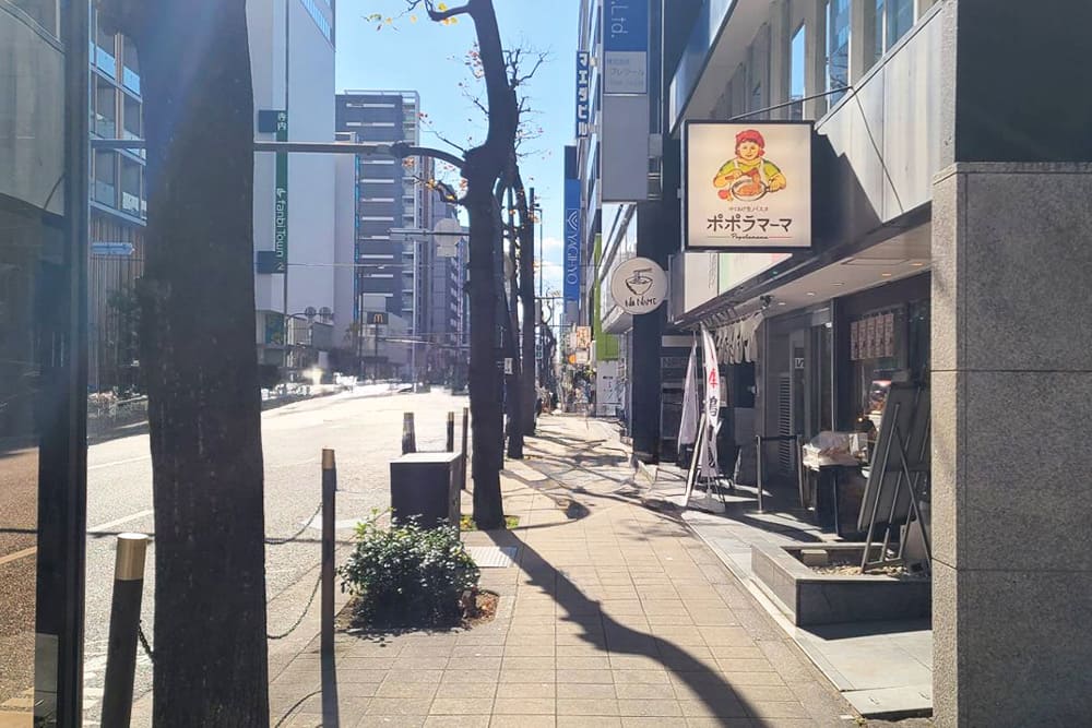 The sidewalk with [Popolamama] on the right.