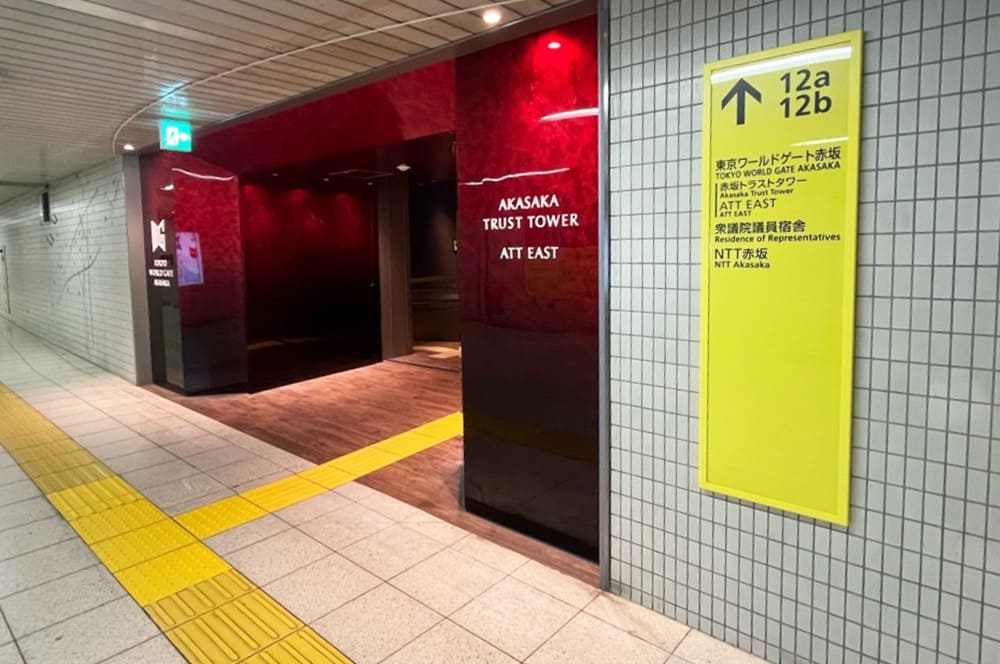 溜池山王駅12b出入口の案内板と、通路の先に広がる赤色の壁が特徴的な「赤坂トラストタワーATT EAST」の入り口。