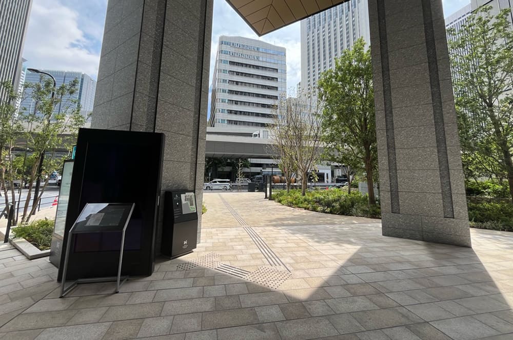 御影石の柱が左右に立ち、正面の奥には白いビルが見える。