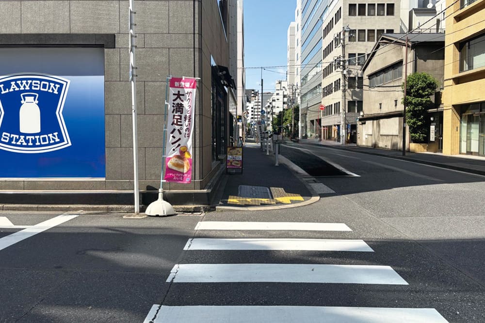 横断歩道。左手にローソン、奥にはオフィスビルが並ぶ。