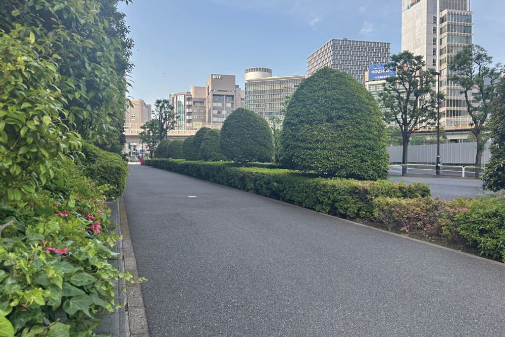 「KKRホテル東京」の前の緑豊かな歩道と街並み。