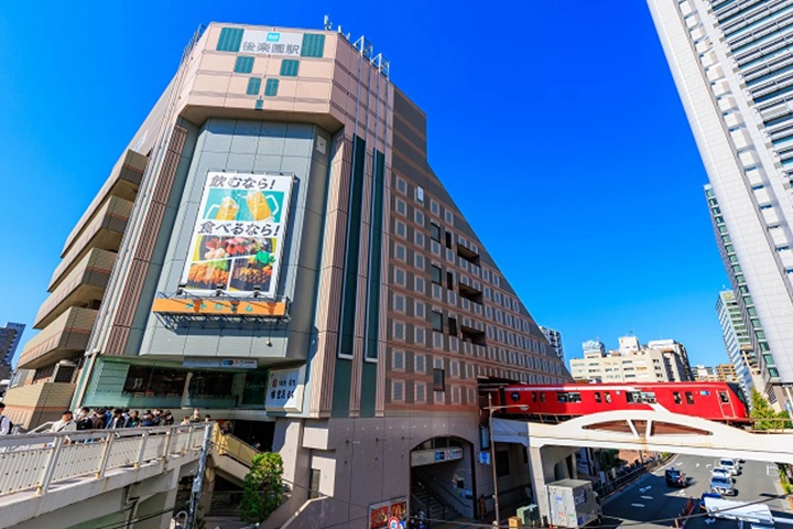 後楽園駅の建物と、その横を高架で走る赤い電車。