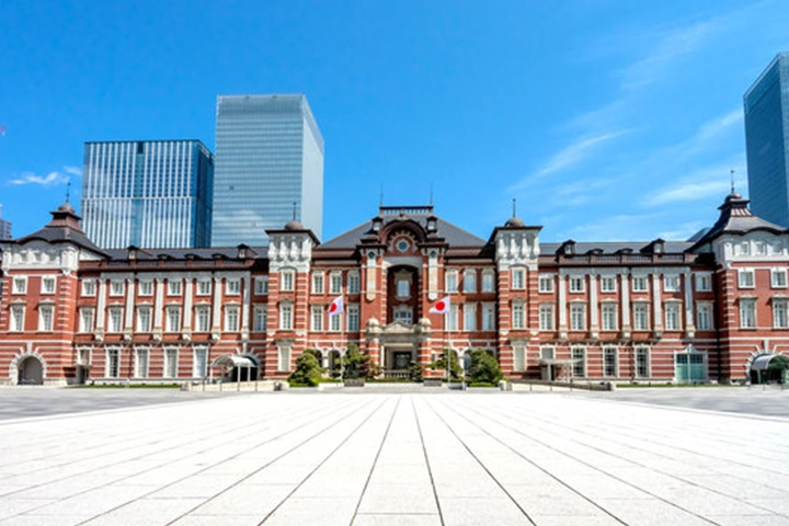 広場越しに見た東京駅の赤レンガ駅舎。背景には近代的な高層ビルがそびえ立つ。