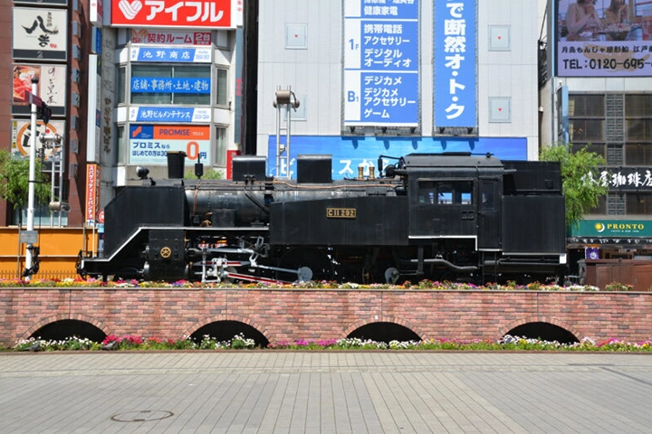 新橋駅前のSL広場に展示された蒸気機関車。花壇の上に置かれ、周囲はビルに囲まれている。