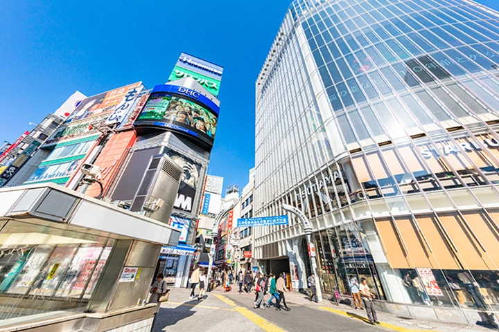 渋谷センター街の入口。様々な看板が並ぶ通りと、隣接するガラス張りの近代的なビル。