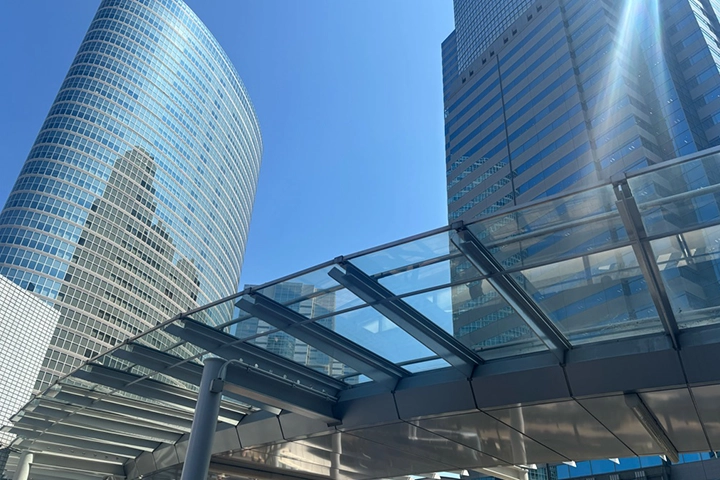 品川駅前の高層ビル群を見上げる構図で、天井がガラス張りの通路が写っている。