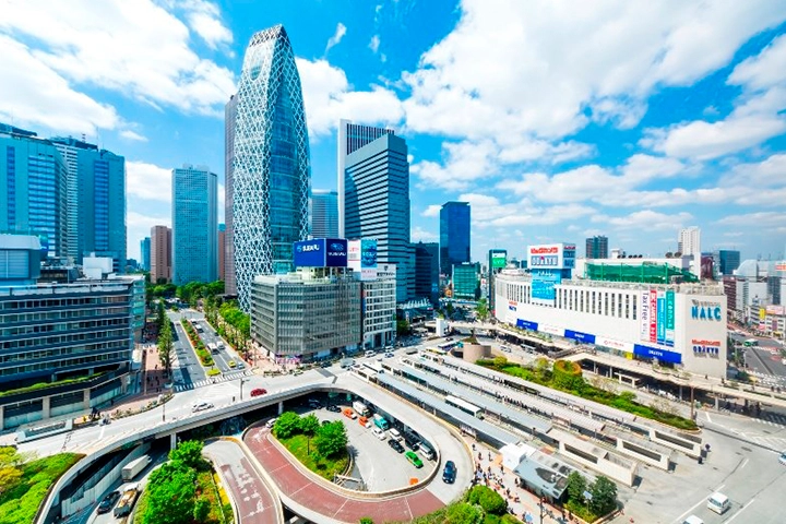 新宿の街並みを高所から見た風景。個性的なコクーンタワーや、道路、バスターミナルが見える。