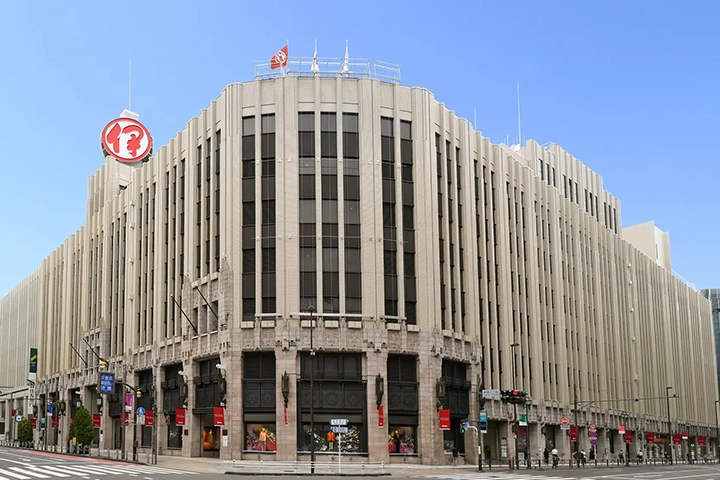新宿伊勢丹本店のレトロな外観。特徴的な縦のラインと、屋上にある赤いロゴが写っている。