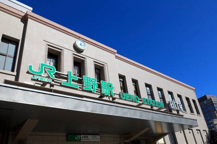 青空の下、JR上野駅の緑色の駅名標が掲げられた駅舎の外観。