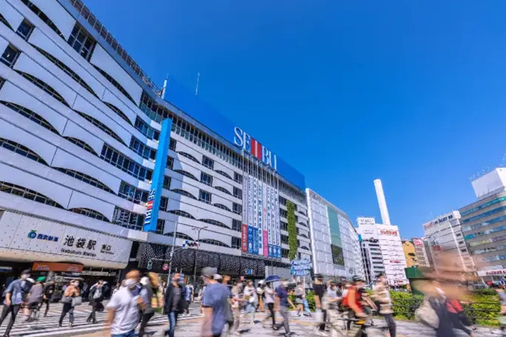 西武デパートと池袋駅が見える駅前広場。多くの人々が行き交い、賑わっている。