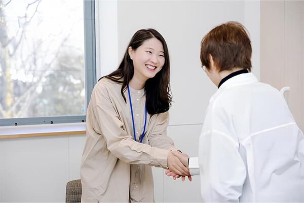 人材紹介の担当者の女性が、笑顔で相手と握手をしている。