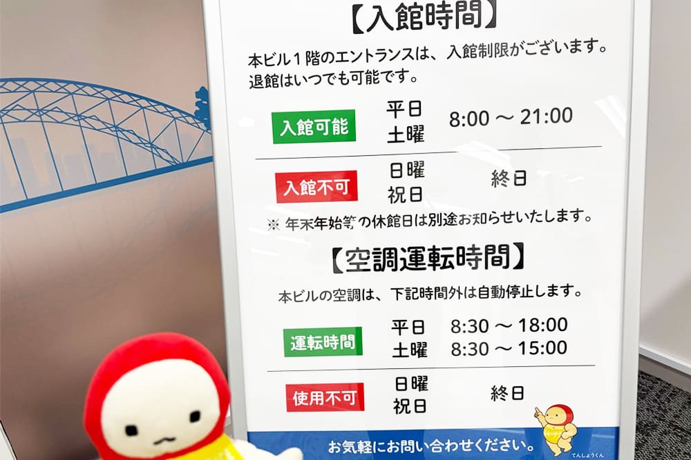 天翔オフィス天王洲ファーストタワーの入館時間、空調運転時間の看板。看板の横にいるてんしょうくんぬい