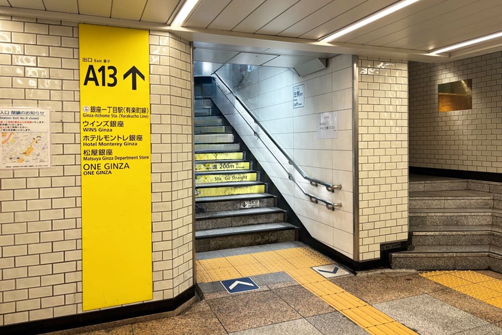 銀座駅A13出口へと続く、黄色い案内板と階段のある地下通路。
