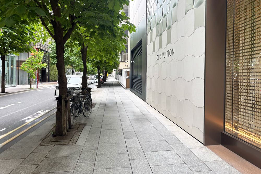 白い幾何学模様のファサードが特徴的なルイ・ヴィトン松屋銀座店の店舗外観と、その奥へ続くブルガリの建物。