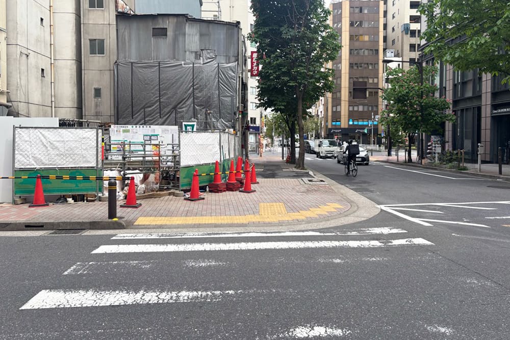 大黒天宝くじ銀座センター跡地の工事現場。手前に横断歩道があり、角地がフェンスや赤いコーンで囲まれている様子。