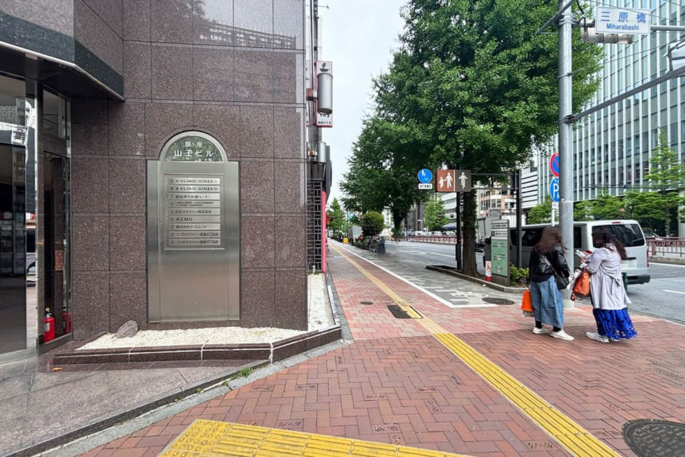 銀座山王ビルと、昭和通りへと続く街路樹のある歩道の風景。